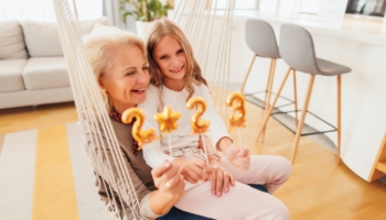 Grandmother and granddaughter holding balloons shaped as numbers 2023